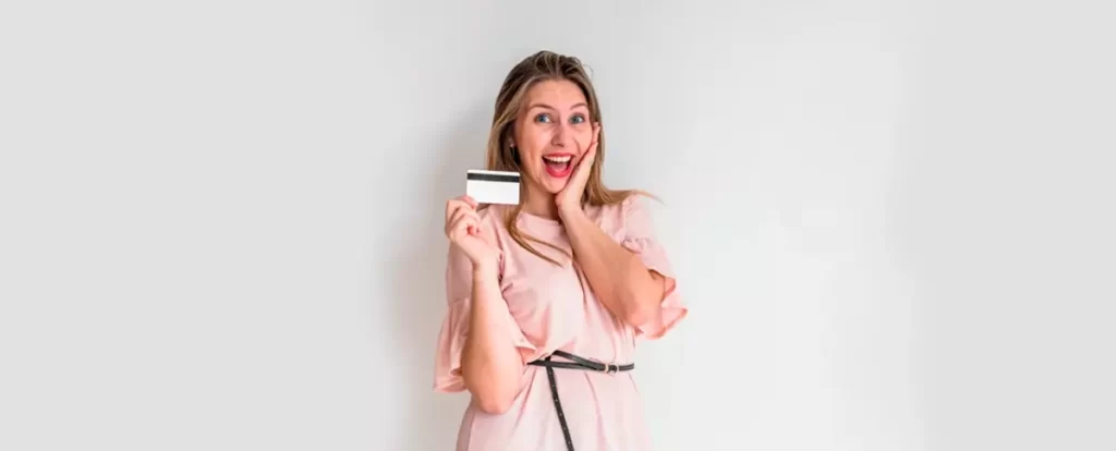 mulher loira feliz com cartão de crédito na mão