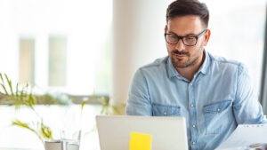 Imagem de homem de negócios mexendo em notebook com post it colado na tela