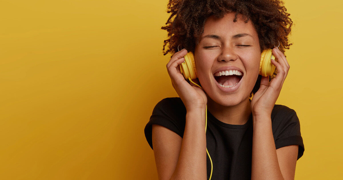 Imagem de mulher negra ouvindo musica com fone de ouvido amarelo