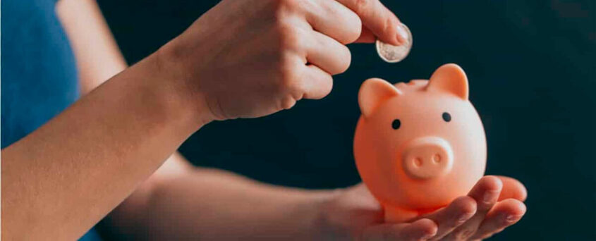 Imagem de mulher colocando moeda no cofrinho de porquinho